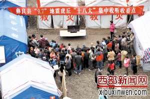 救灾帐篷前,安置点的群众观看十八大直播 新华社 图
