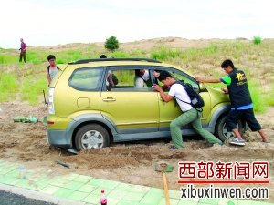 在运送火箭过程中,汽车陷在沙里,航天爱好者们一起用手推车。